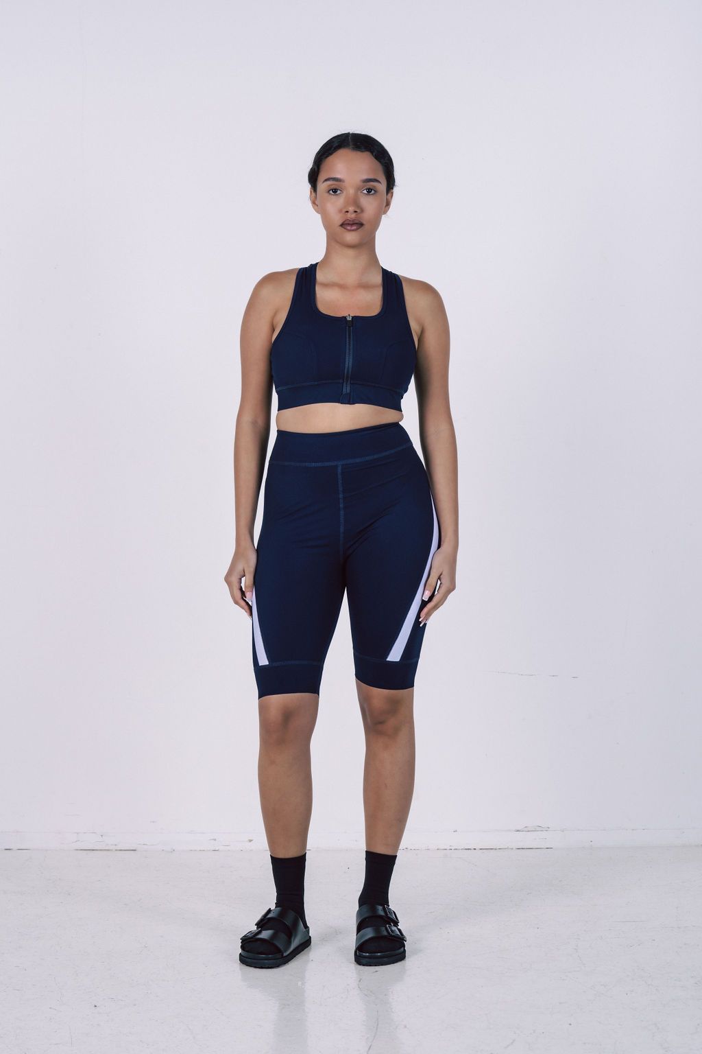 Navy-blue-seamless-cycling-set- with-white-stripes-featuring-a-zip-up-sports-bra-and-compression- cycling-shorts-for-women's-fitness